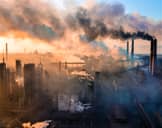 Overhead view of an industrial complex emitting thick smoke from the chimneys