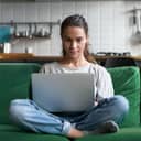 Woman sitting on a couch with legs crossed an a laptop in her lap