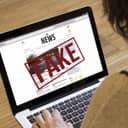 News article labeled as fake displayed on a laptop monitor