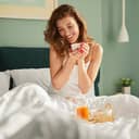 A happy woman having a breakfast in bed
