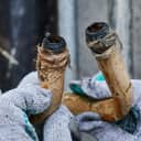 close-up of a rusty, corroded, bent plumbing pipes held by a plumber wearing work gloves