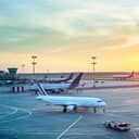Numerous airplanes parked on the runway at an airport