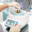 close-up of a scientist placing a sample into a medical centrifuge machine in a lab