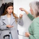Dissatisfied old woman, owner of apartment, receiving keys from married couple tenants