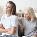 two women sitting in their living room with elderly mother scolding her adult daughter