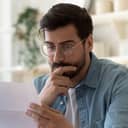 close-up of a worried man reading something from the paper he's holding in his hand