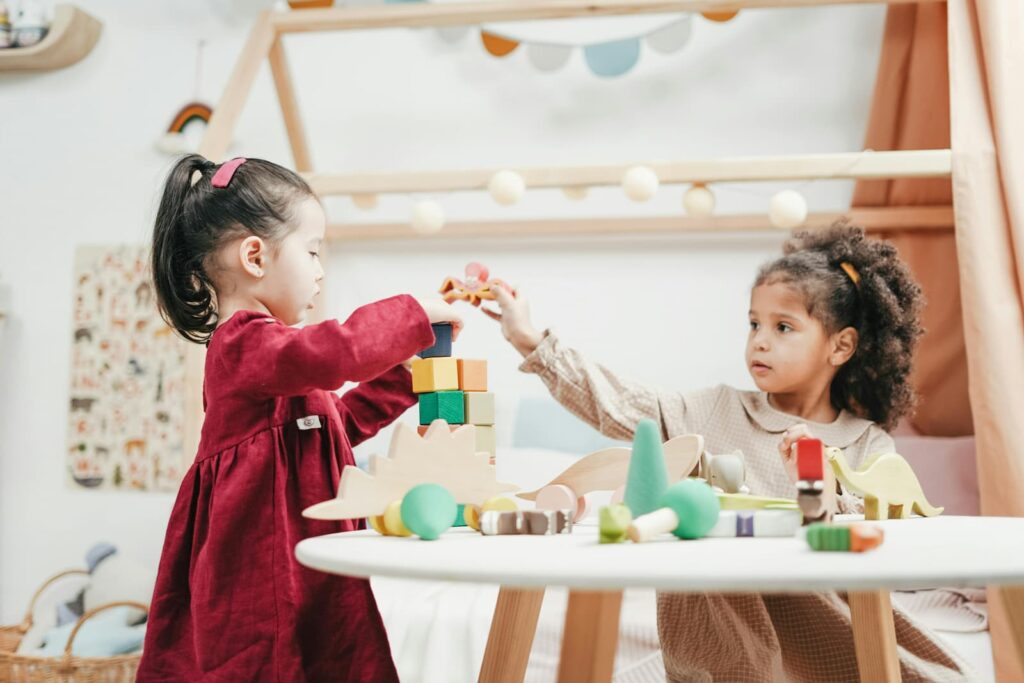 Two little girls playing with blocks on a table