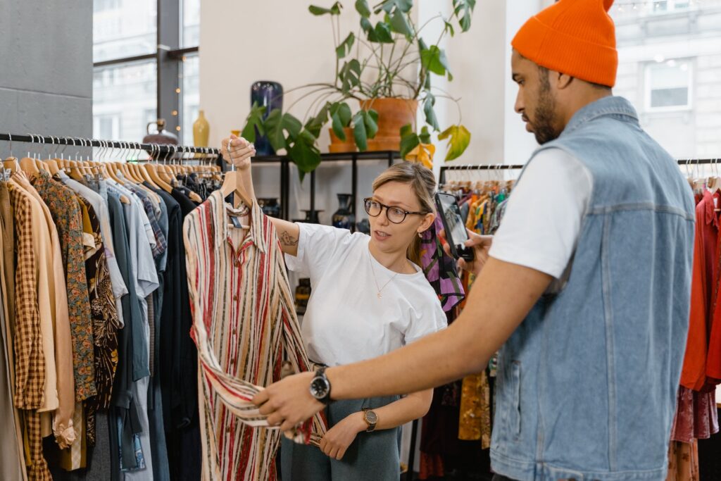 A worker in a clothing store showing a shirt to a customer