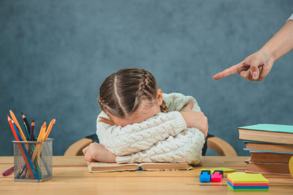 A young schoolgirl being judged harshly by a teacher because of her mistakes